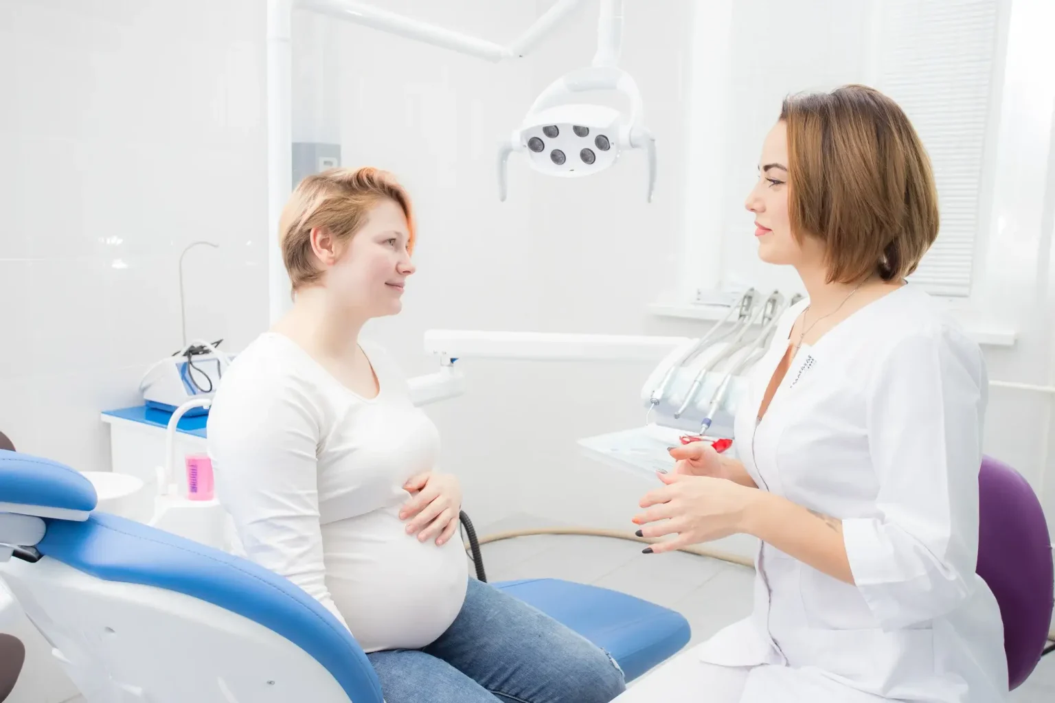 Trudna žena sjedi na stomatološkoj stolici dok joj stomatologinja objašnjava pregled i brigu o oralnom zdravlju tijekom trudnoće