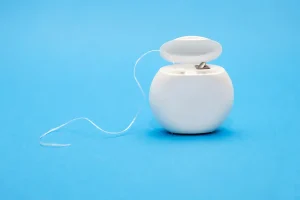 Zobna nitka v škatlici na modri podlagi.