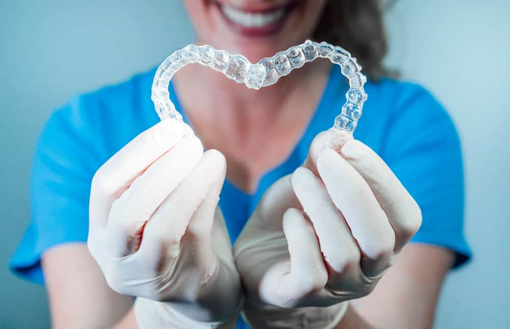 Ortodont drži dva Invisalign aparatića oblikovana u srce.